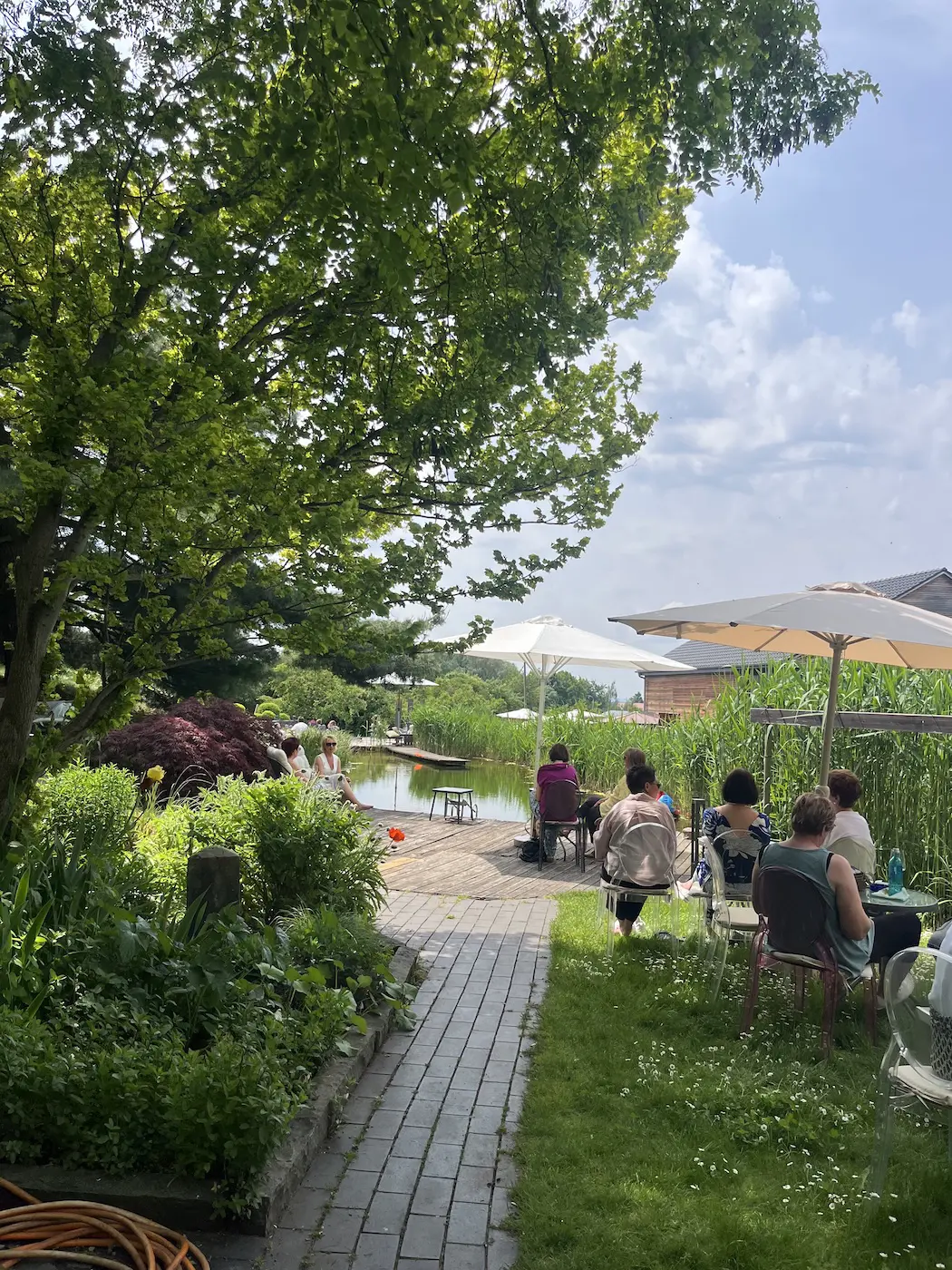 Terrasse des Weinguts mit Sonnenschirmen, Stehtischen und Gästen vor dem Holzgebäude